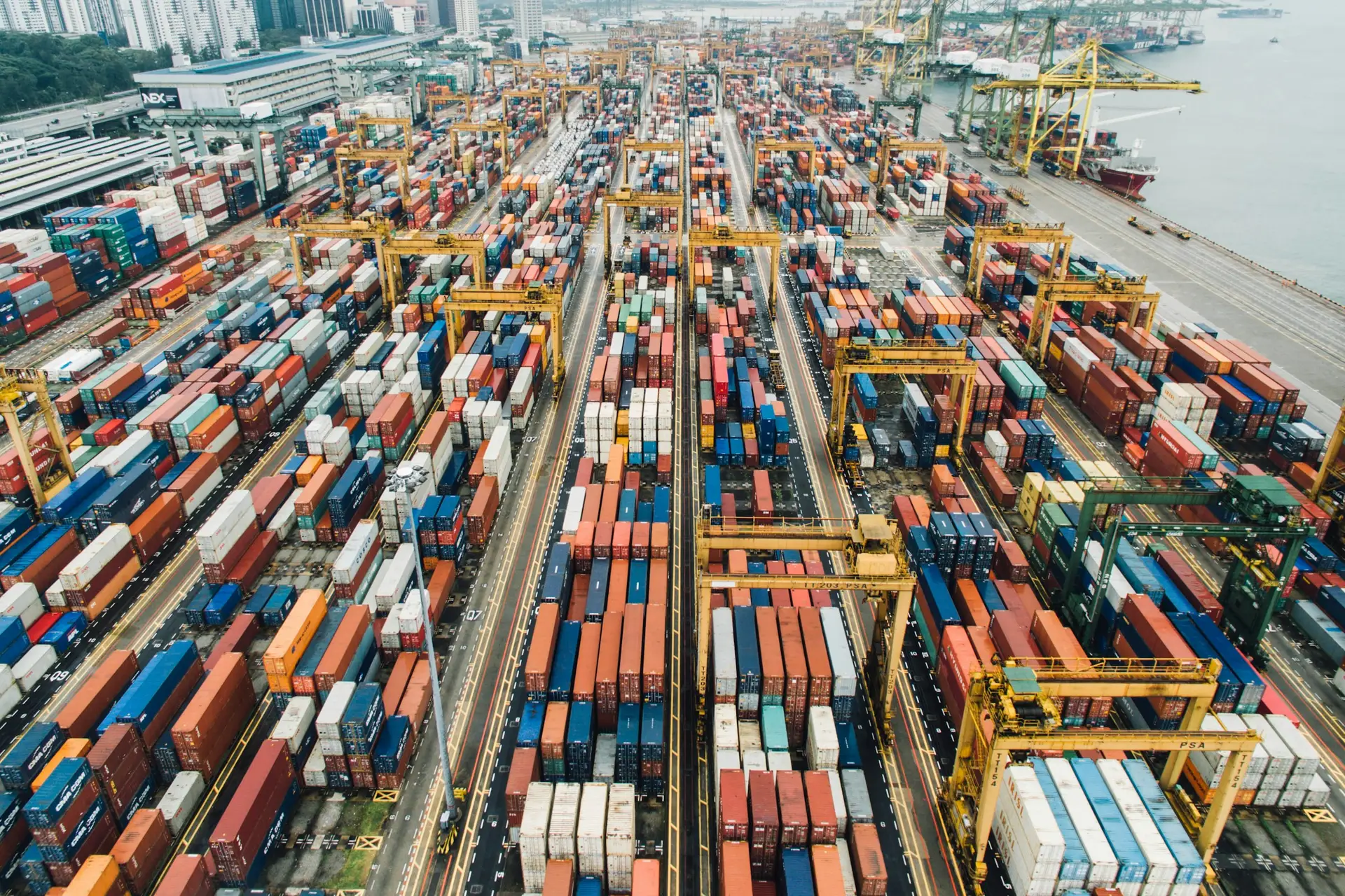 Aerial view of a container port with cranes and stacked shipping containers